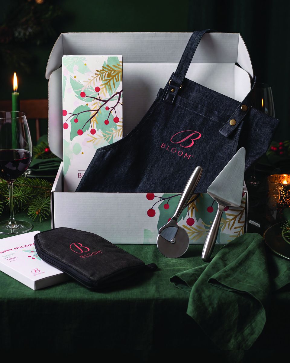Geschenkset Around the Table: geöffnete Geschenkbox mit Pizzaset, Kühltasche und Schürze auf einem Weihnachtstisch